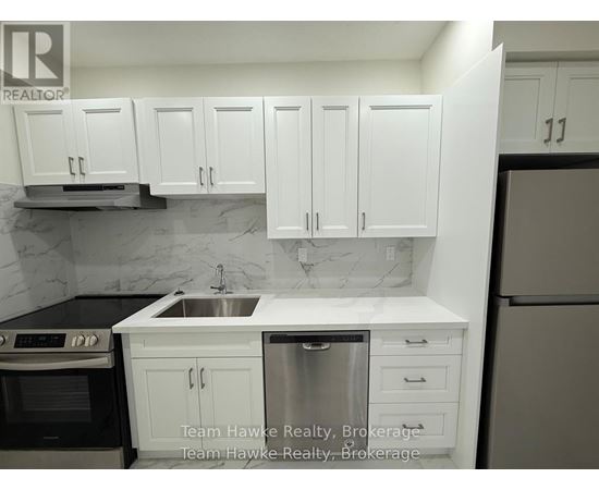 A kitchen with white cabinets and a marble backsplash.