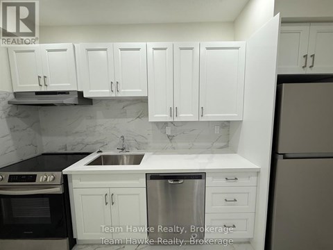 A kitchen with white cabinets and a marble backsplash.