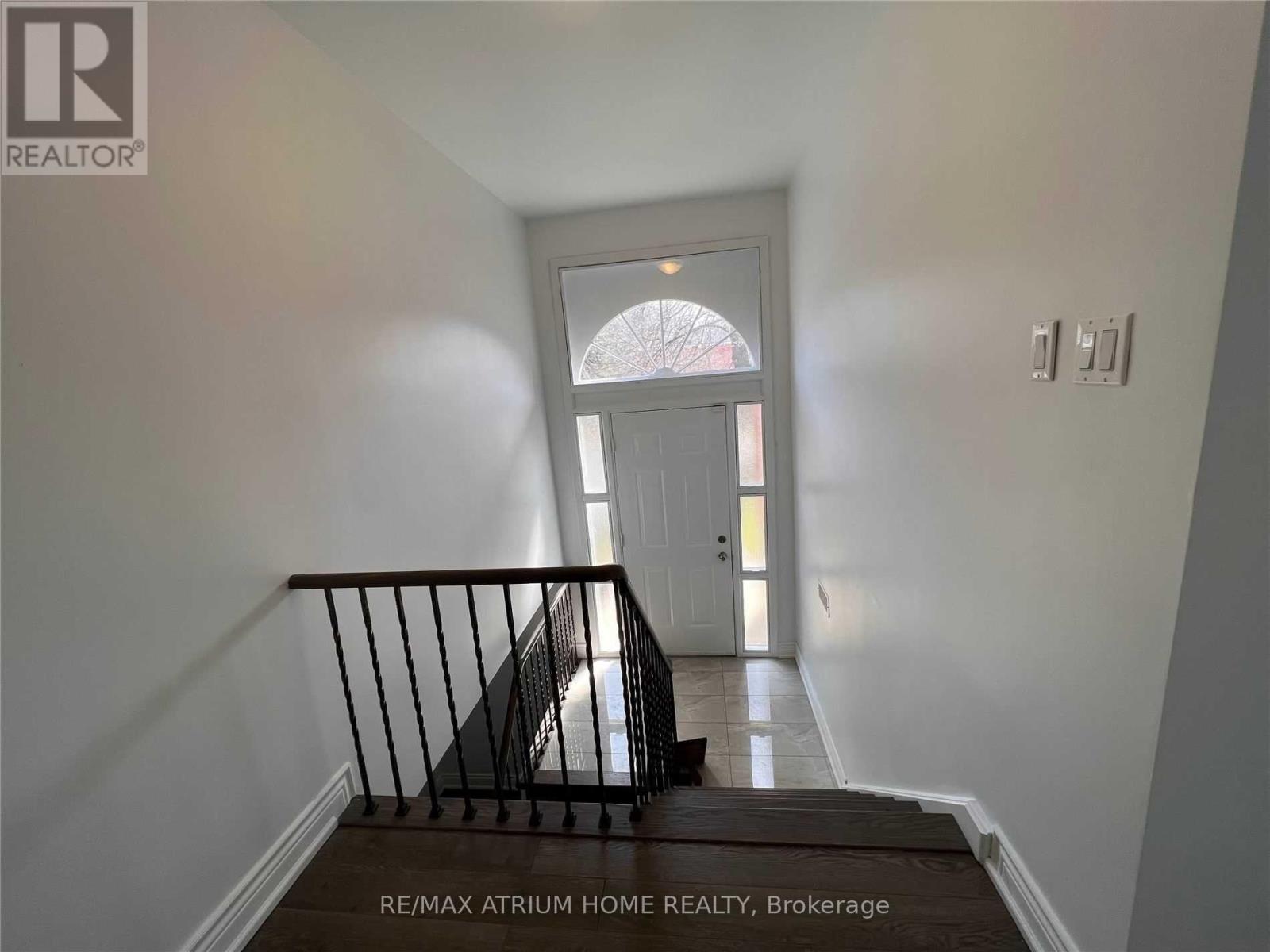 A hallway with a staircase leading to a door with a window above it.