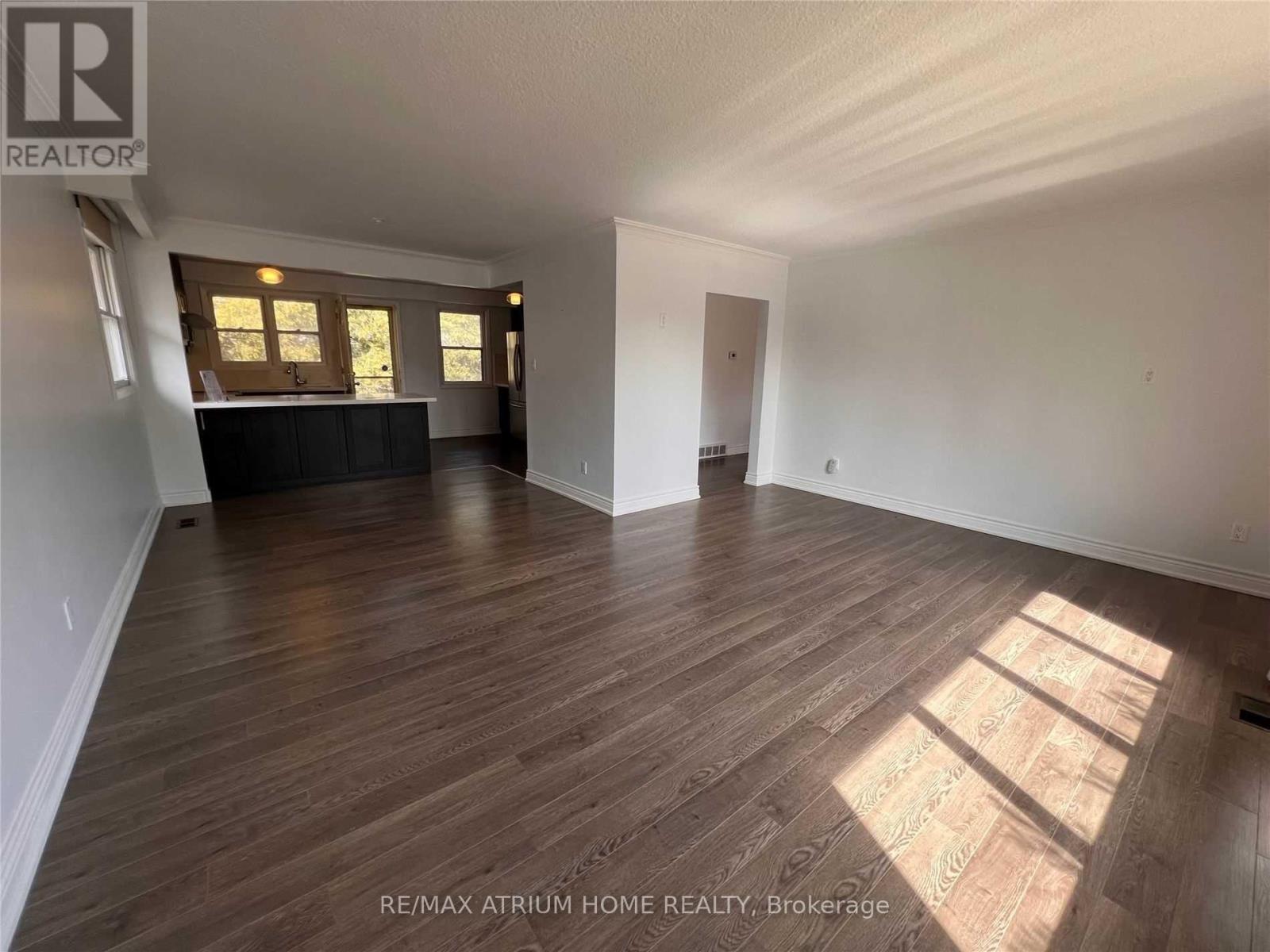 A spacious room with wooden flooring and a large window allowing sunlight to stream in.