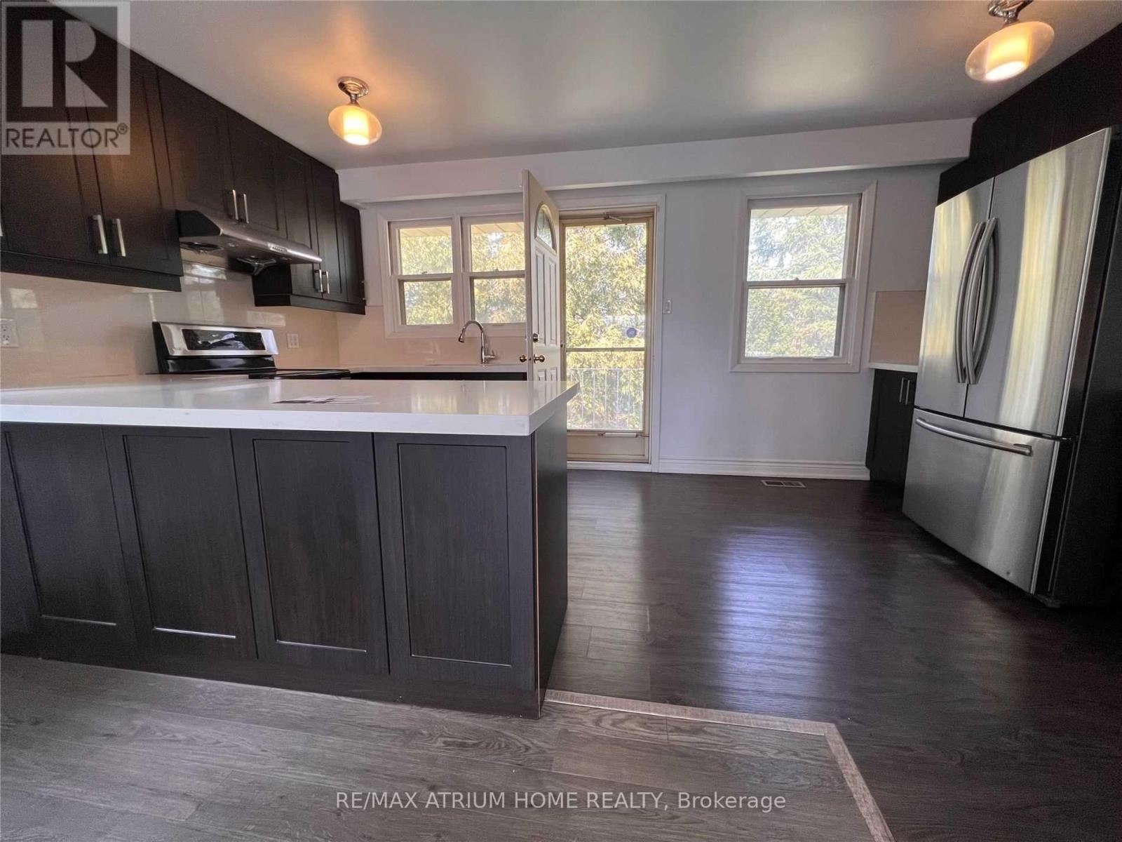 A kitchen with dark wood cabinets and a stainless steel refrigerator.