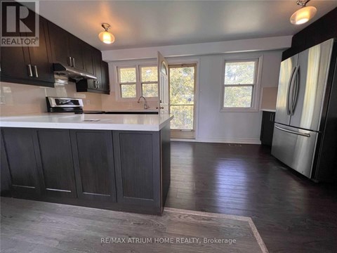 A kitchen with dark wood cabinets and a stainless steel refrigerator.