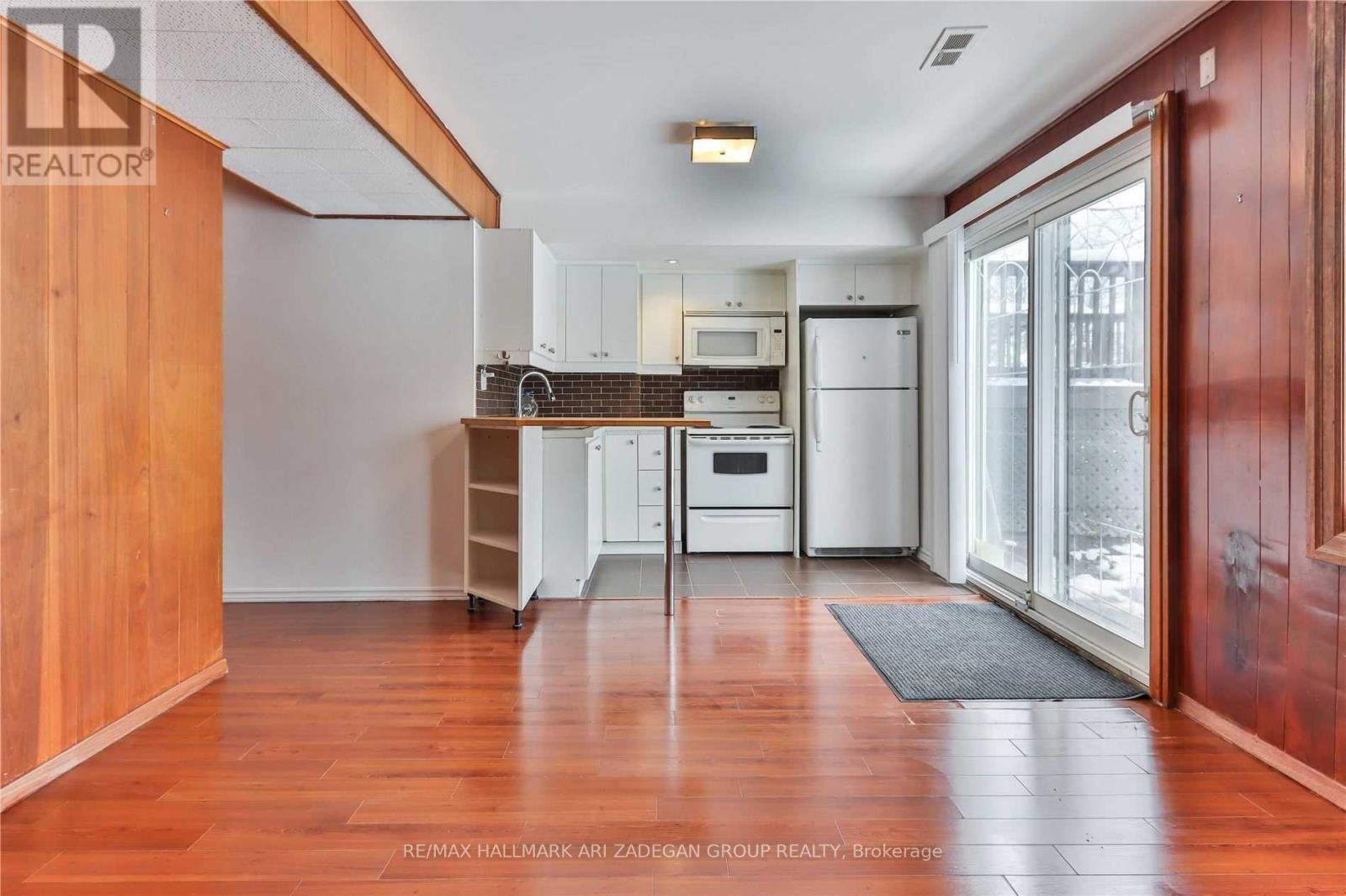 A kitchen with white appliances and wooden floors.