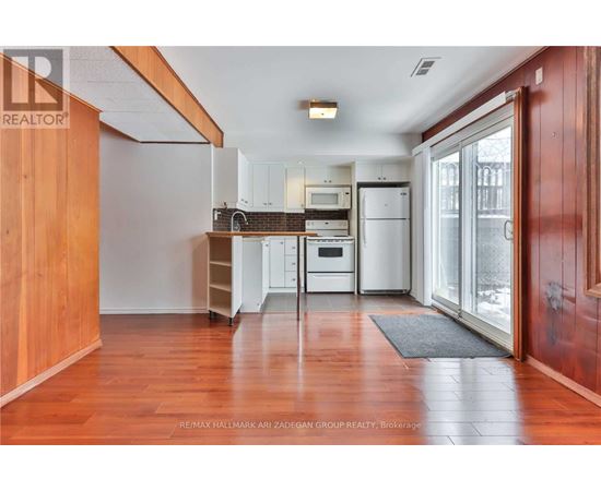 A kitchen with white appliances and wooden floors.
