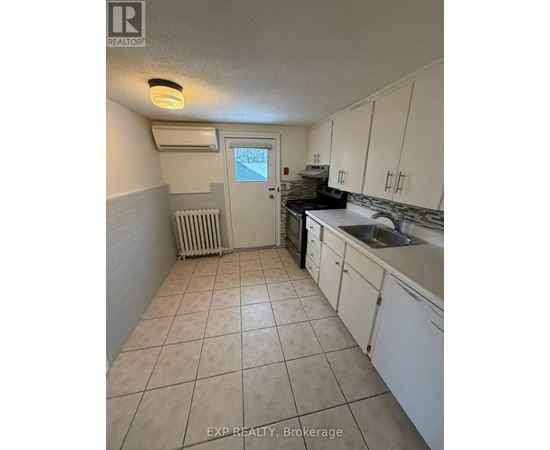 A kitchen with white cabinets and a tiled floor.