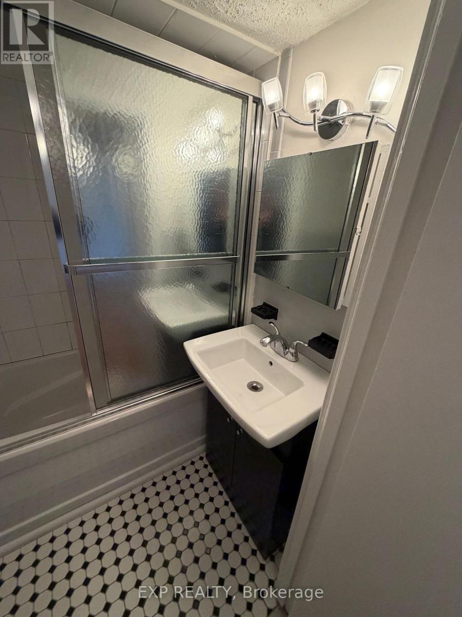 A bathroom with a sink, mirror, and shower.