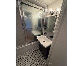 A bathroom with a sink, mirror, and shower.