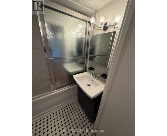 A bathroom with a sink, mirror, and shower.