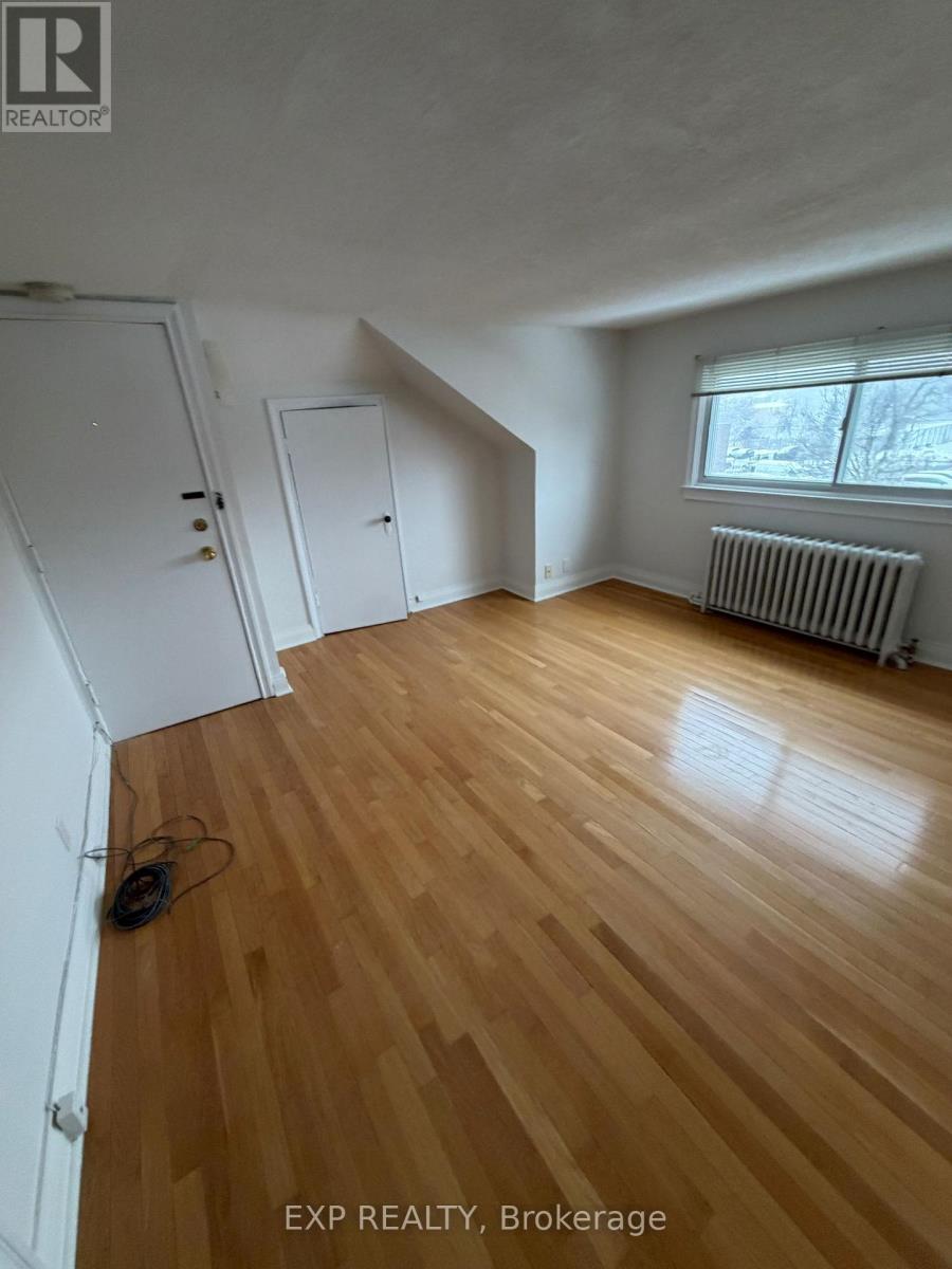 A room with wooden flooring and a window with blinds.