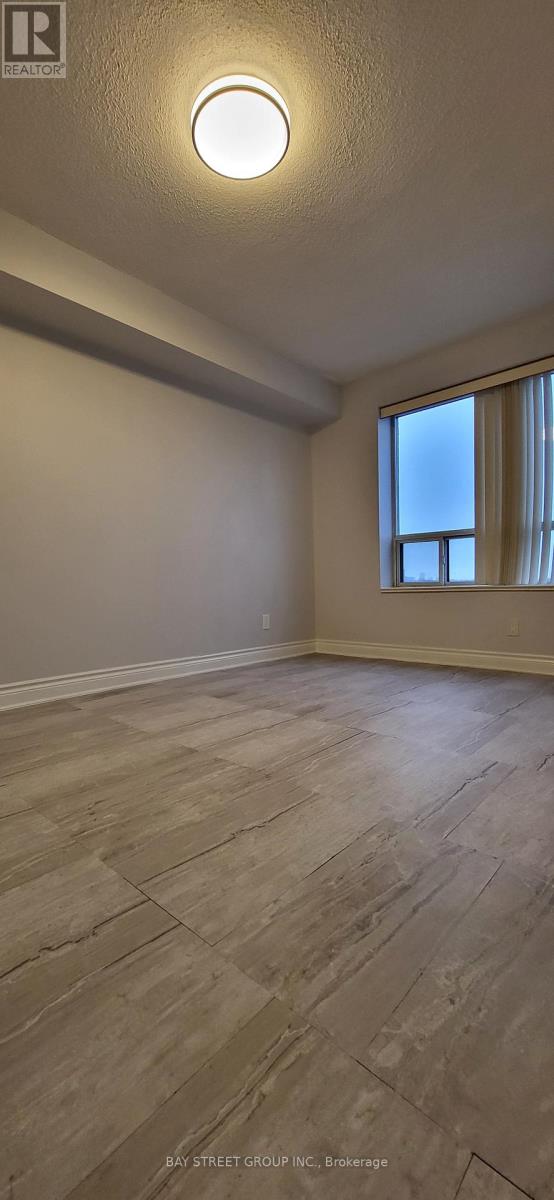 A room with a light on the ceiling and a window with blinds.