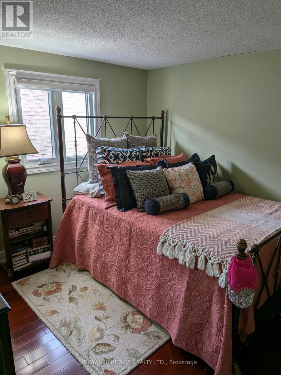 A bedroom with a bed covered in a pink comforter and a lamp on a nightstand.