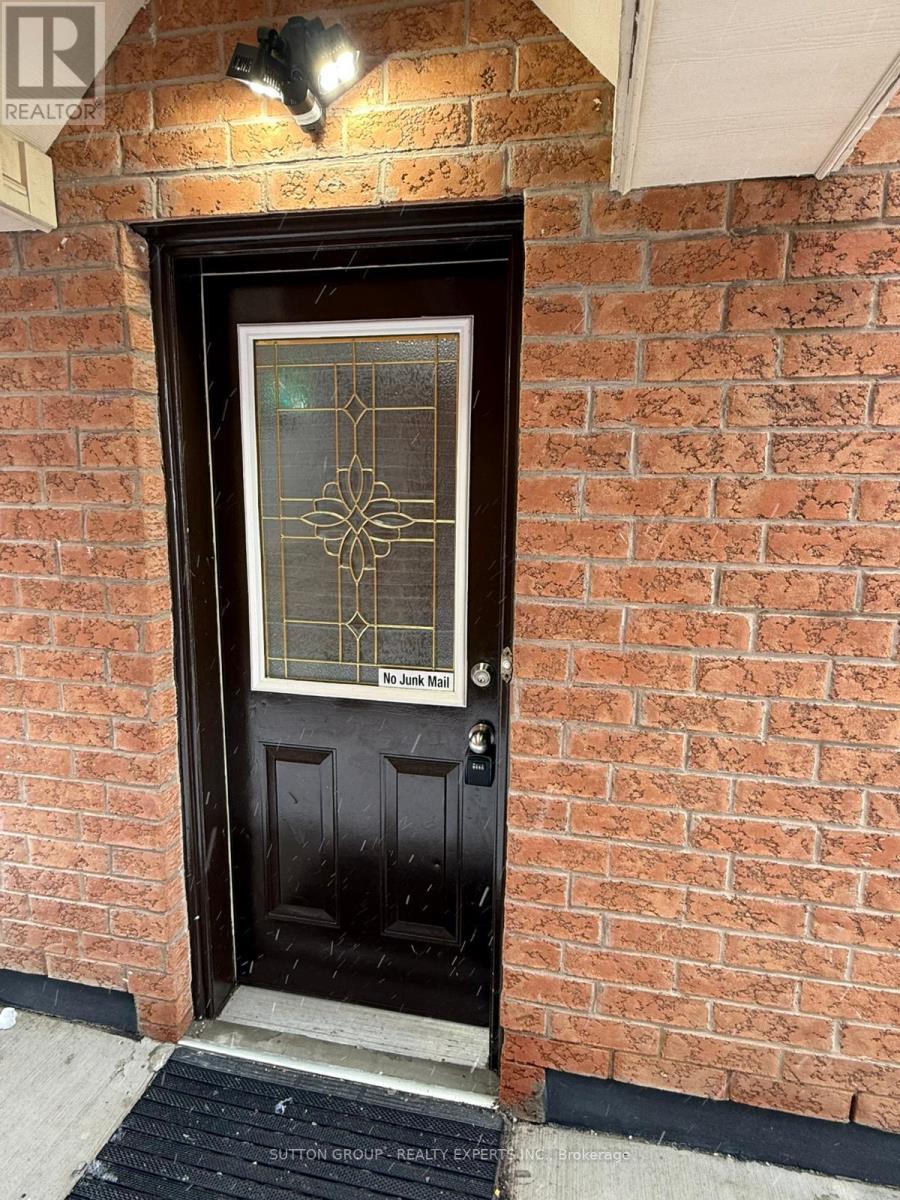 A black door with a glass window and a brick wall.