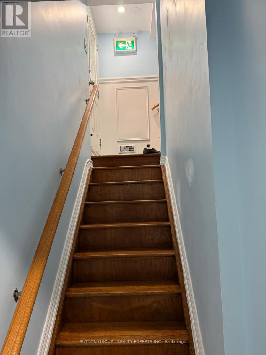 A staircase leading to a white door with a green exit sign above it.