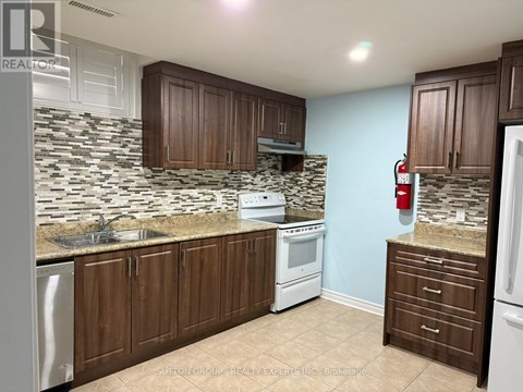 A kitchen with brown cabinets and a stone backsplash.