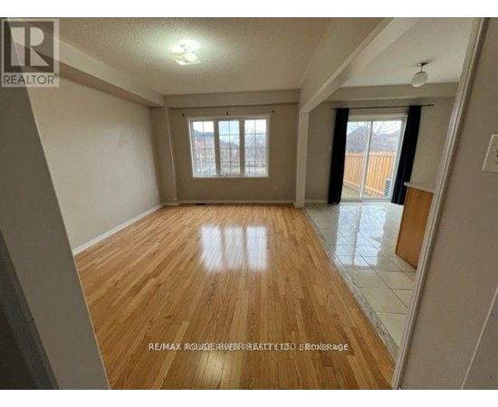 A spacious room with wooden flooring and a large window.