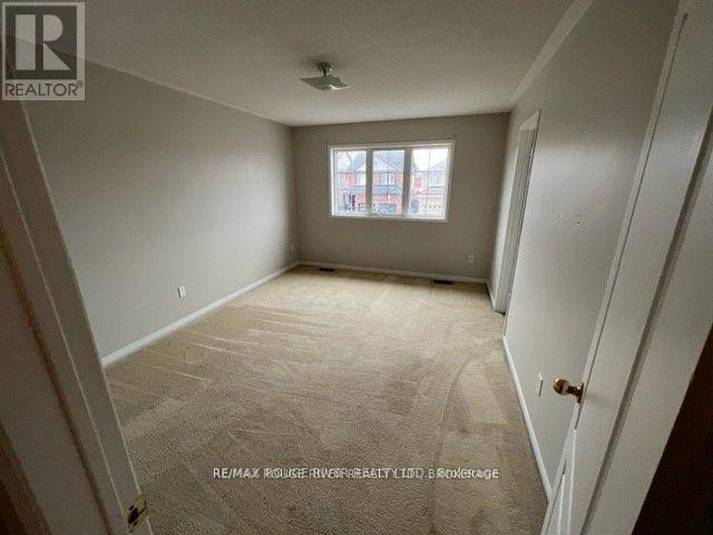 A room with a carpeted floor and a window with a view of a building outside.