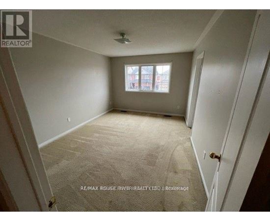 A room with a carpeted floor and a window with a view of a building outside.