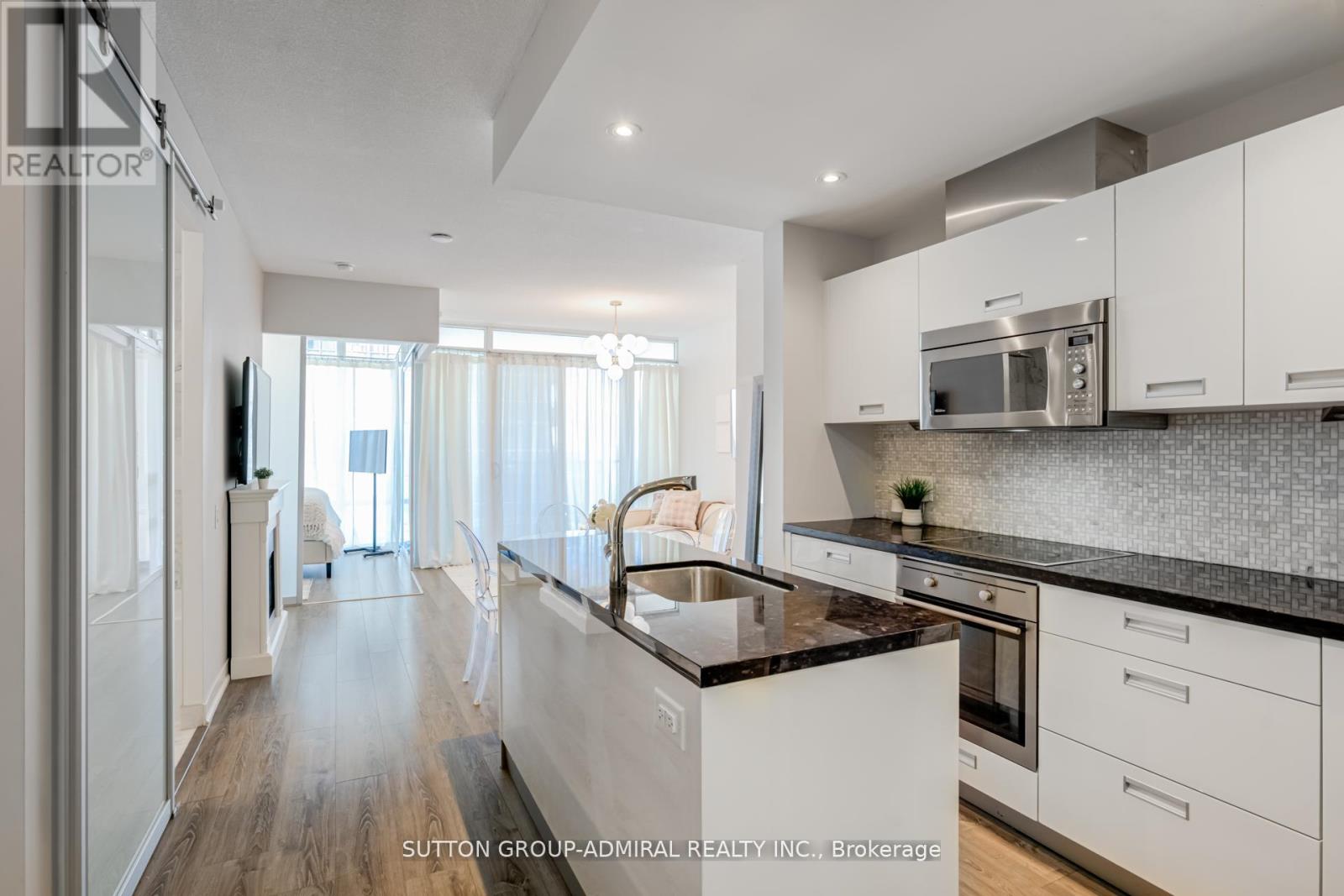 A modern kitchen with white cabinets and black countertops.