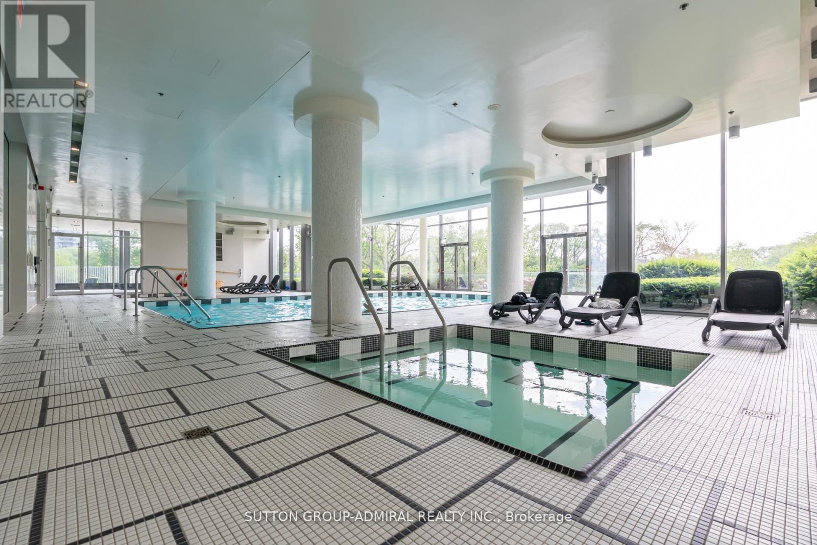 A large indoor swimming pool with a glass bottom and tiled floor.