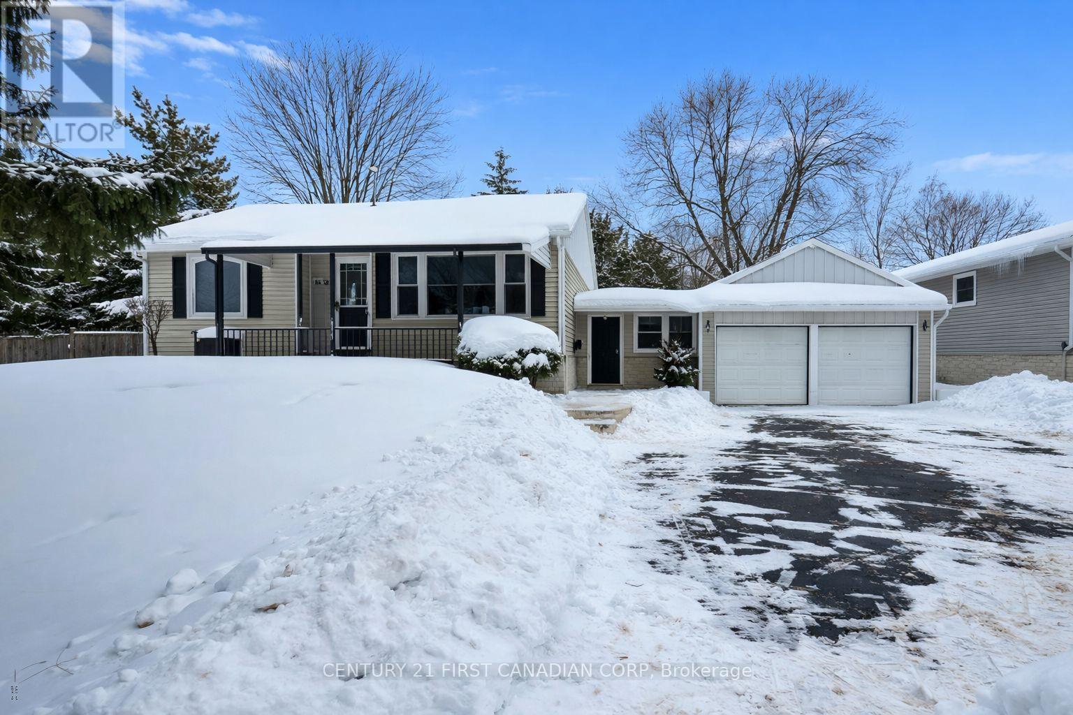 A house with a snow-covered driveway in front.