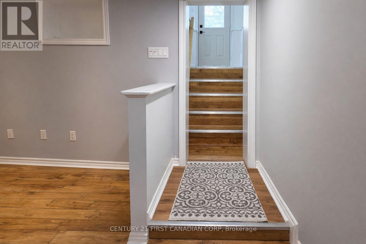A hallway with a staircase and a rug on the floor.