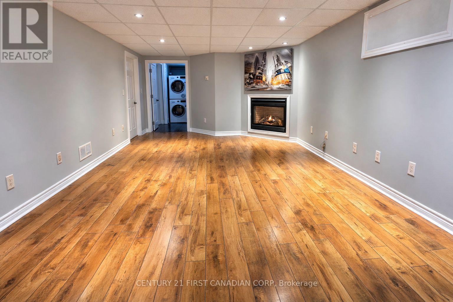 A spacious room with wooden flooring and a fireplace.