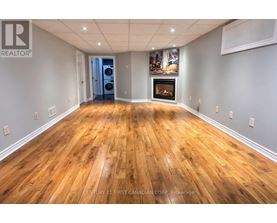 A spacious room with wooden flooring and a fireplace.