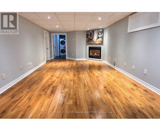 A spacious room with wooden flooring and a fireplace.
