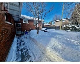 A snow-covered yard with a tree and a house in the background.