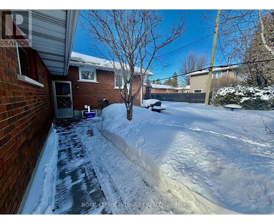 A snow-covered yard with a tree and a house in the background.