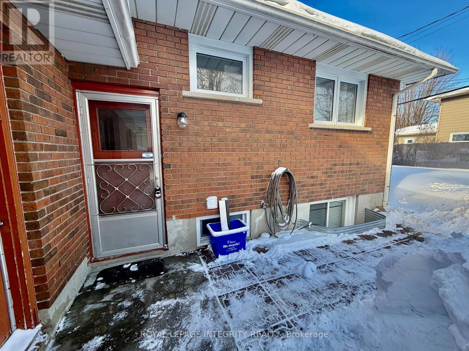 A red door with a glass window is on a brick house.