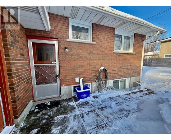 A red door with a glass window is on a brick house.