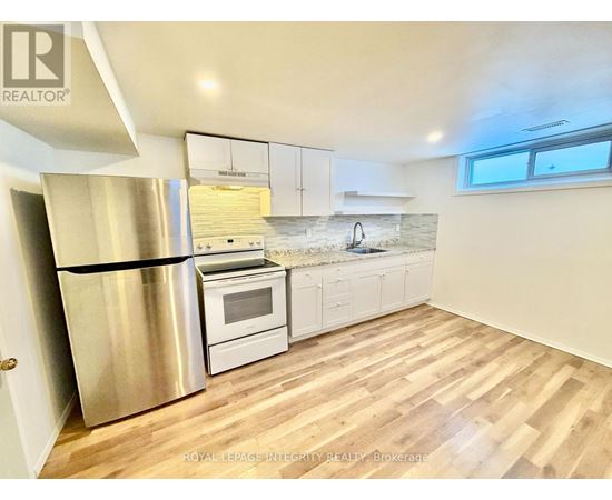 A kitchen with a stainless steel refrigerator and wooden flooring.
