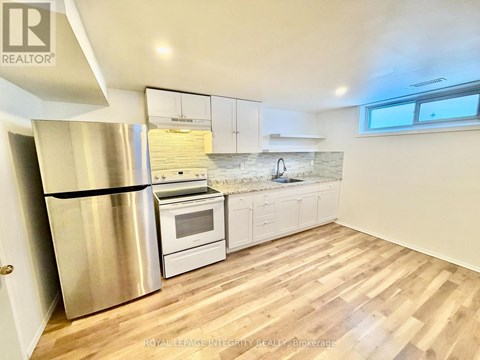 A kitchen with a stainless steel refrigerator and wooden flooring.
