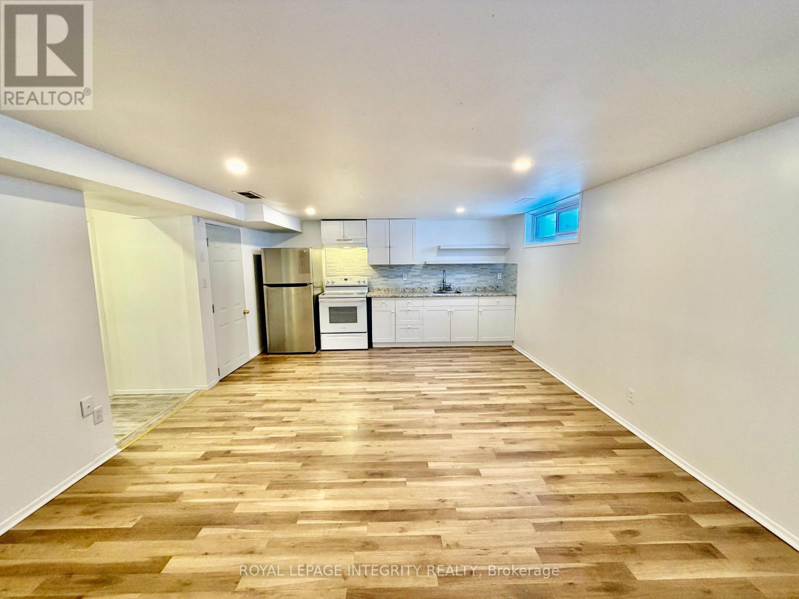 A spacious room with wooden flooring and white walls.