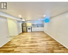 A spacious room with wooden flooring and white walls.