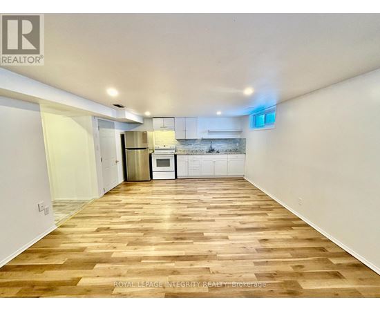 A spacious room with wooden flooring and white walls.