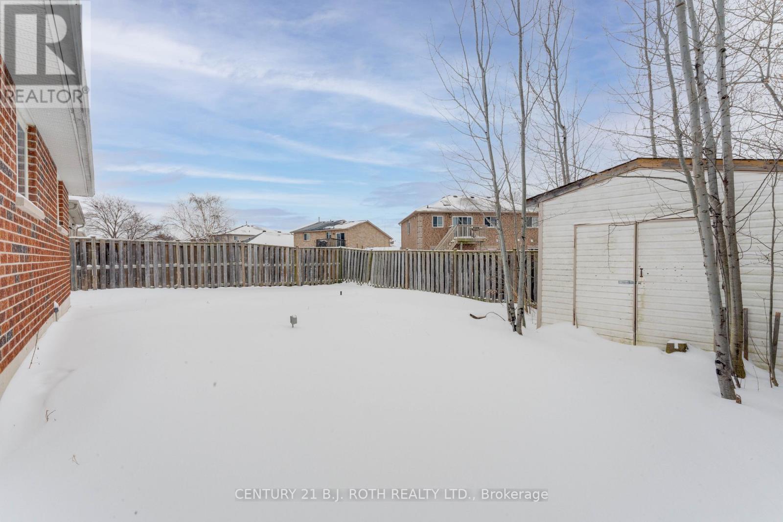 A snow-covered yard with a fence and a building in the background.