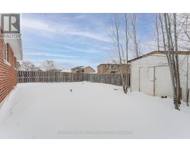 A snow-covered yard with a fence and a building in the background.