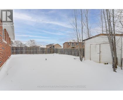 A snow-covered yard with a fence and a building in the background.