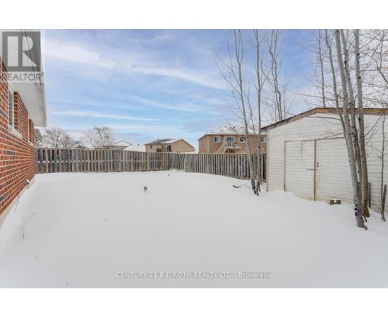 A snow-covered yard with a fence and a building in the background.