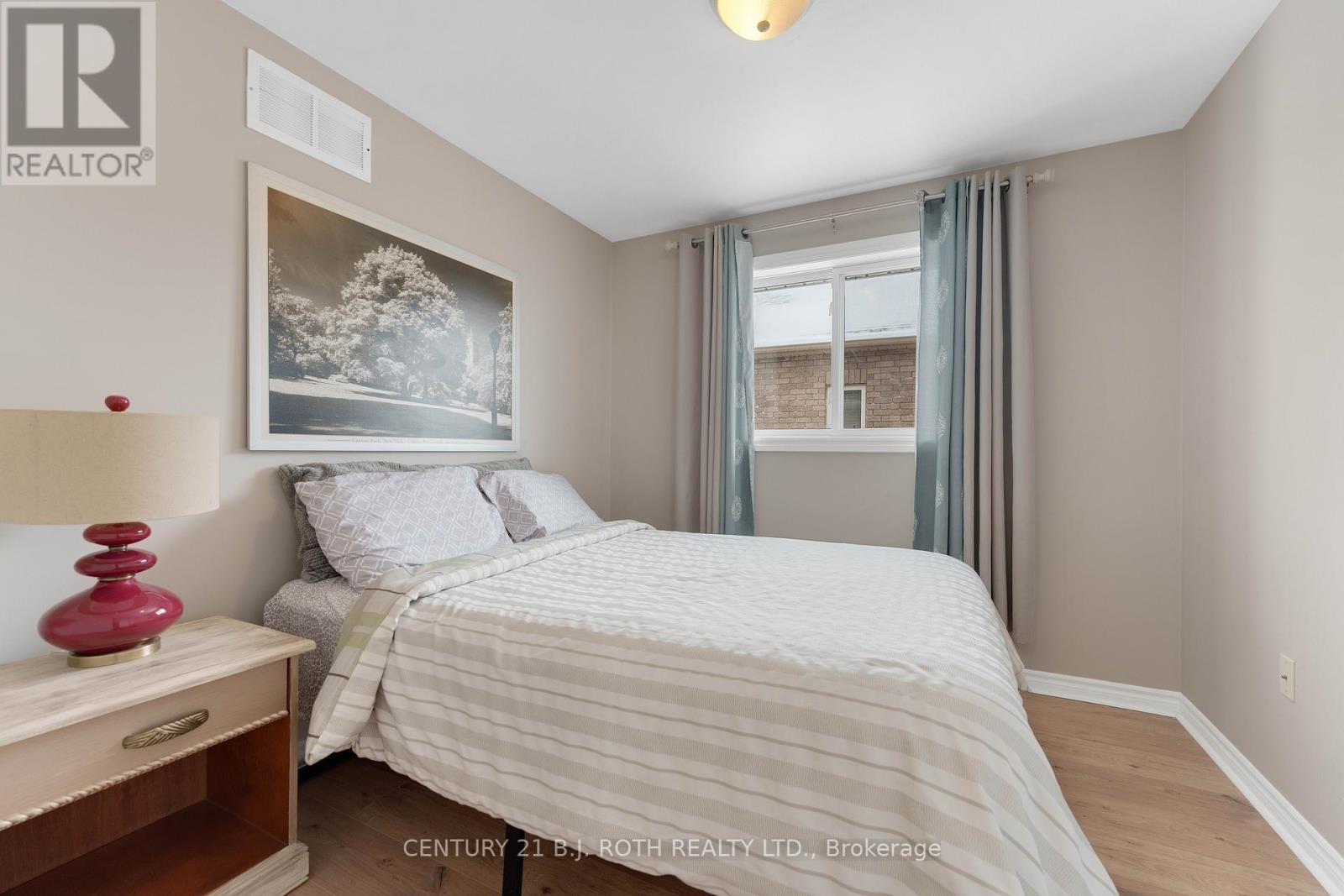 A bedroom with a bed, nightstand, and a painting on the wall.
