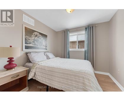 A bedroom with a bed, nightstand, and a painting on the wall.