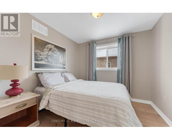 A bedroom with a bed, nightstand, and a painting on the wall.
