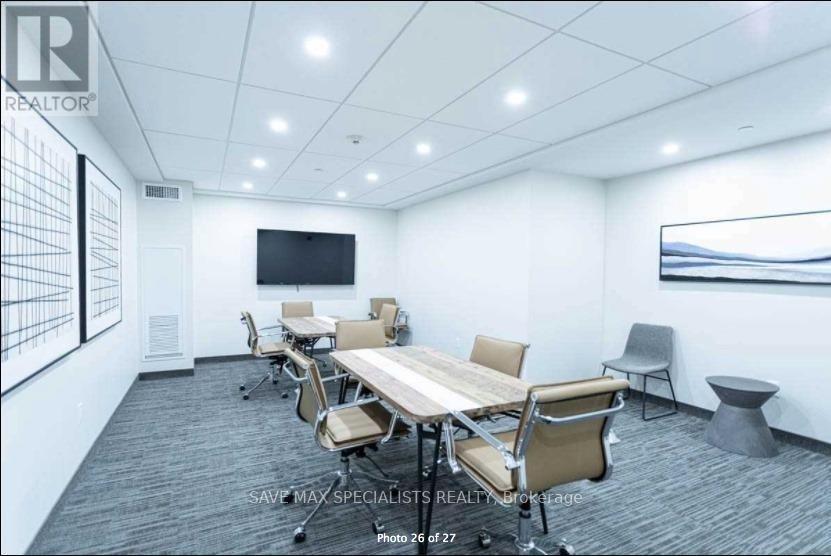 A conference room with a long table and chairs, a flat screen TV on the wall, and a painting hanging above the TV.