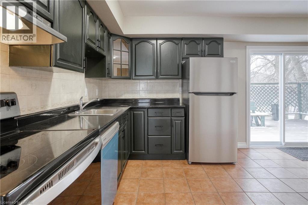 A kitchen with black cabinets and a refrigerator.