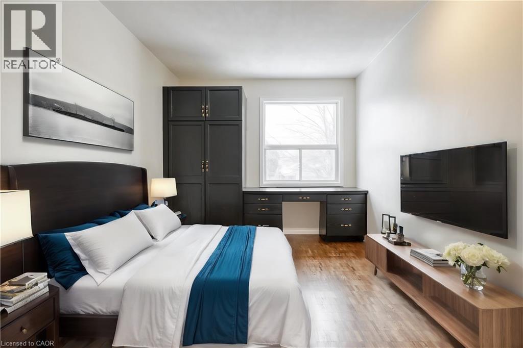 A bedroom with a large bed, a ceiling fan, and a nightstand with a lamp.