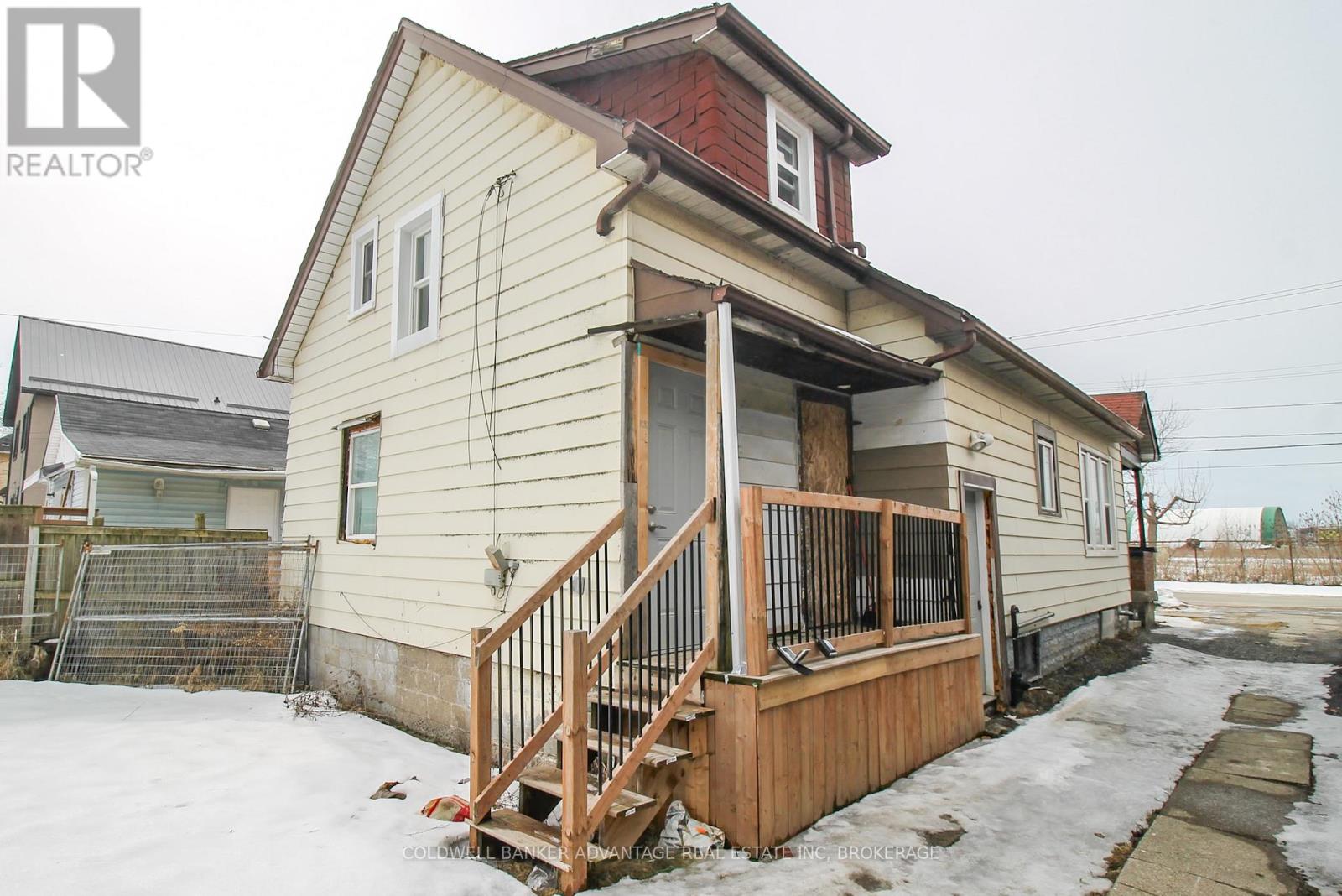 A house with a red roof and a wooden deck in the snow.