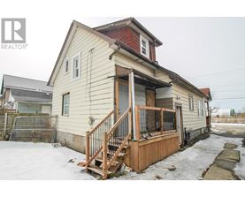 A house with a red roof and a wooden deck in the snow.