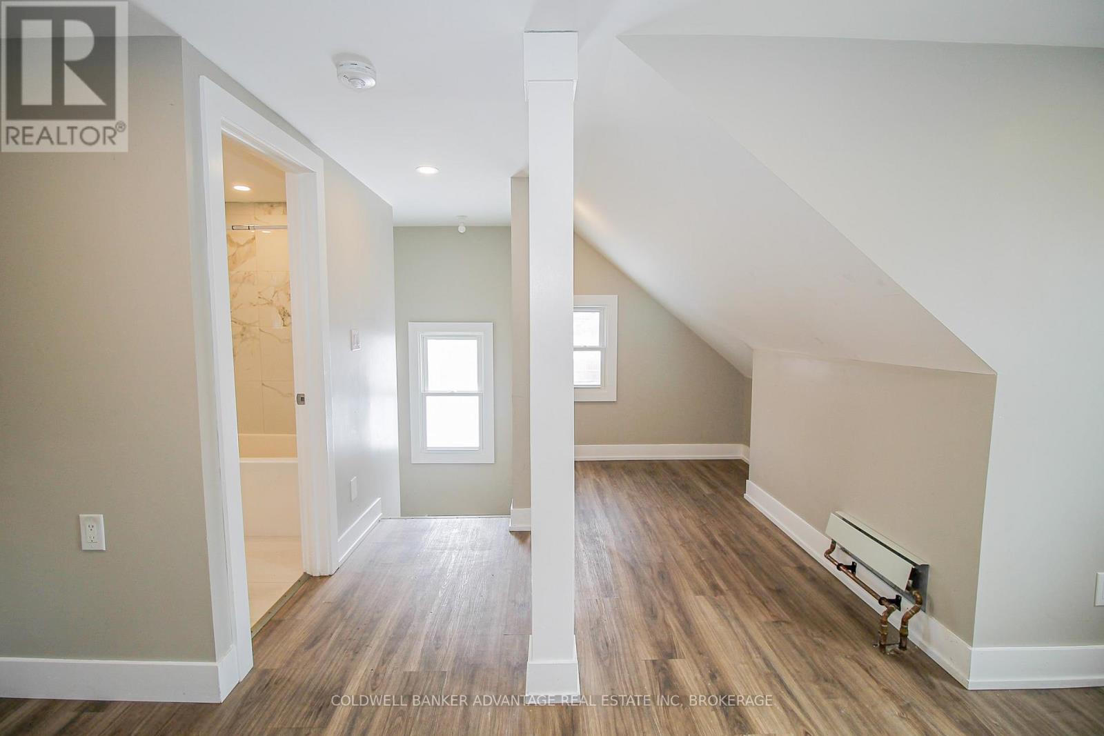 A spacious room with wooden floors and white walls.